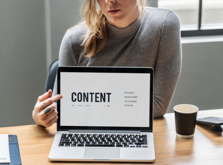 Creator pointing at a laptop screen with the word content while planning content repurposing strategies.