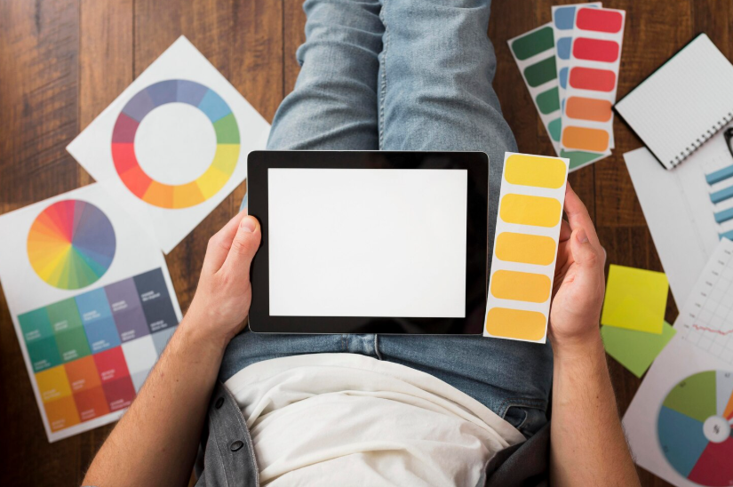 Creator sitting on floor with tablet and color swatches while experimenting with creative aesthetic cohesion.