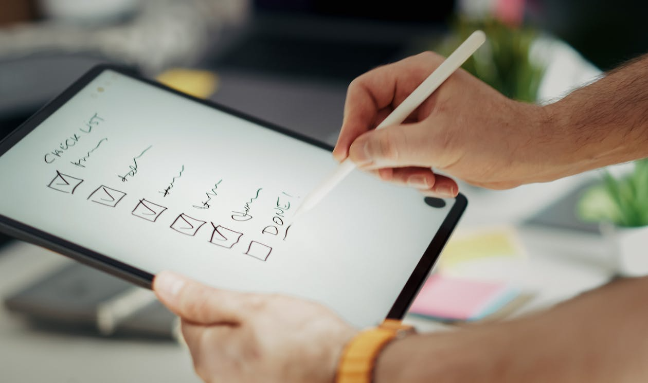 Creator marking tasks as done on a digital checklist, tracking progress to finish creative projects.