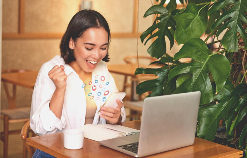 Excited creator checking her phone and celebrating early success from a soft launch strategy.