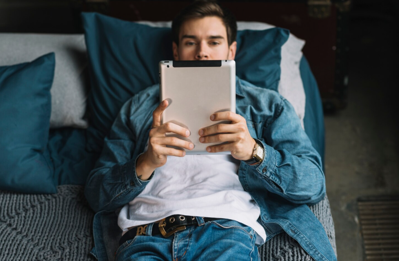 Young man reading on a tablet, illustrating how online readers engage with writing that captures their attention.