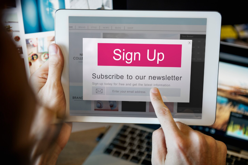 Person tapping a sign up popup on a tablet to subscribe to an email newsletter for creators.